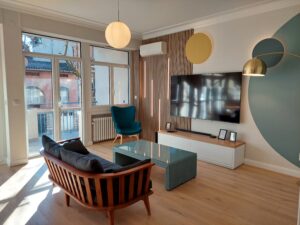 Espace coworking lumineux avec canapé rétro, fauteuil design et écran mural à La-Forge Toulouse